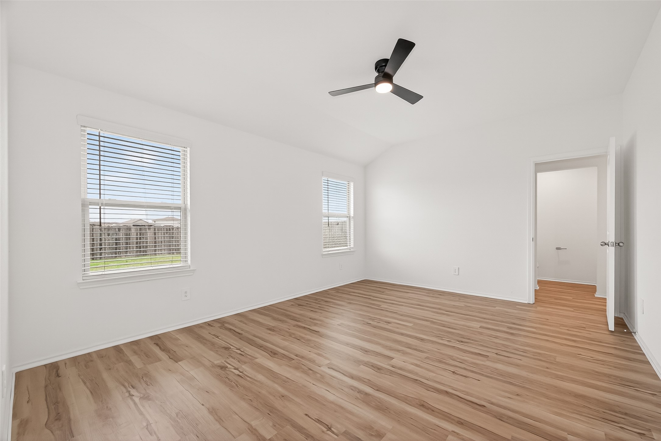 21522 Violet Ridge Road Katy, TX 77449 - Photo 25 of 39 Spacious primary bedroom features fresh white walls, sleek wood flooring, and a new modern ceiling fan. Natural light pours in through the window, enhancing the open feel.