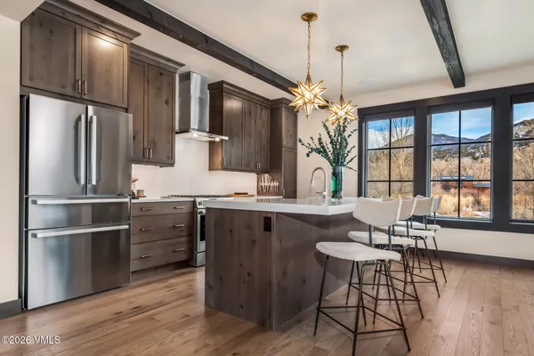 a kitchen with stainless steel appliances granite countertop a refrigerator a stove and a wooden floors