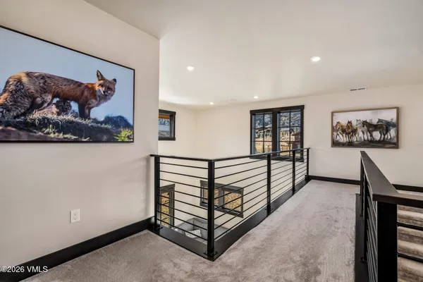 a view of a hallway with a large mirror and paintings on the wall