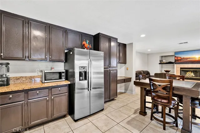 a kitchen with stainless steel appliances granite countertop a refrigerator a stove a sink a dining table and chairs