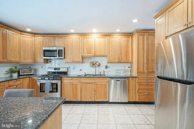 a kitchen with stainless steel appliances granite countertop a stove a sink and a refrigerator