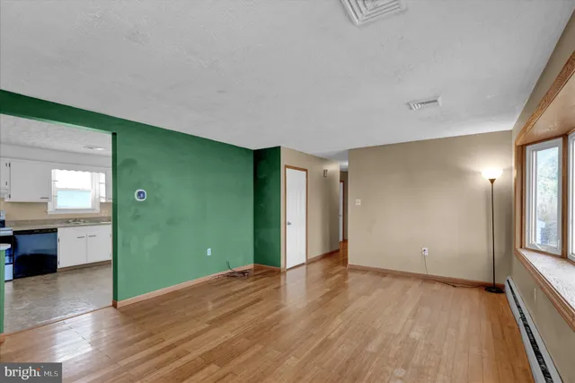 a view of an empty room with window and wooden floor