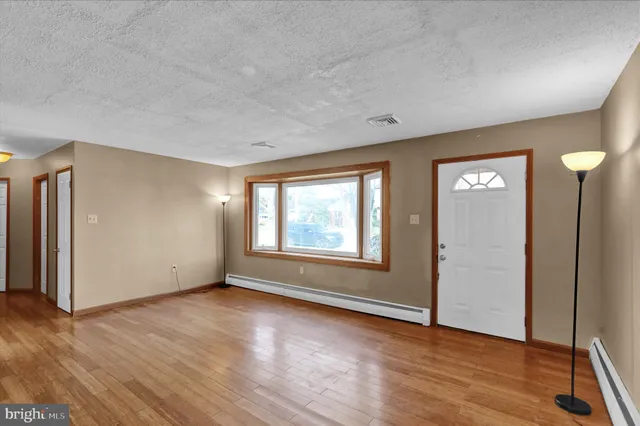 an empty room with wooden floor and windows