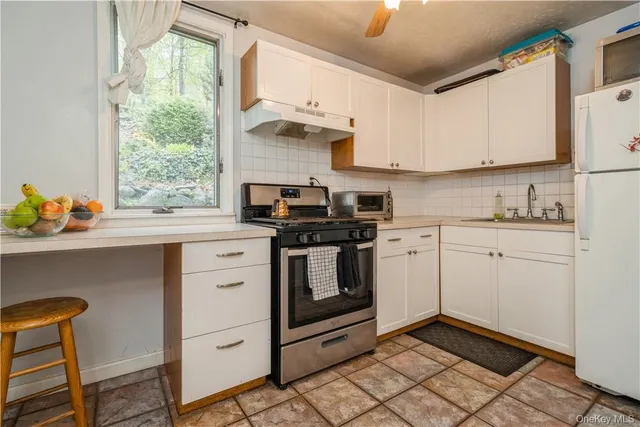 a kitchen with granite countertop a sink appliances cabinets and a window