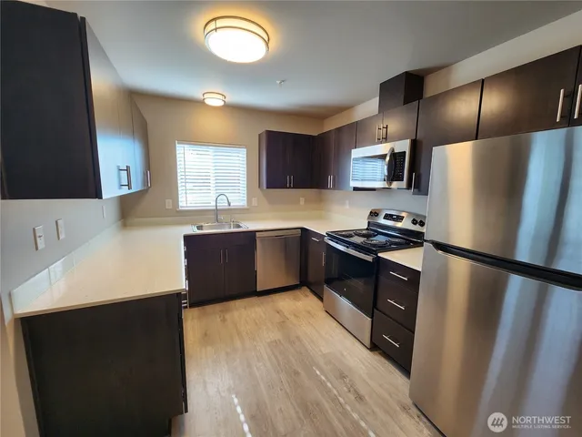 a kitchen with stainless steel appliances a refrigerator a sink a stove a microwave a counter top and space