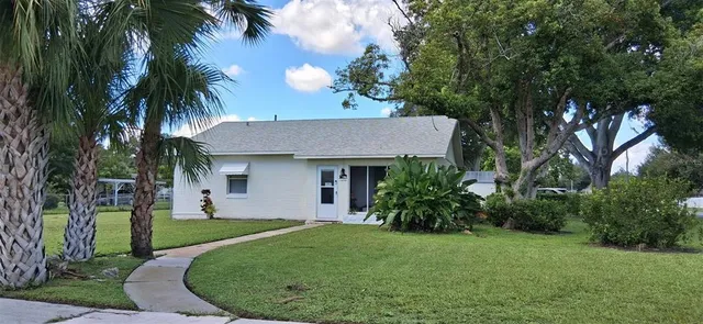 a view of a house with a yard potted plants and palm trees