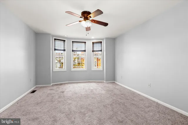 an empty room with windows and ceiling fan