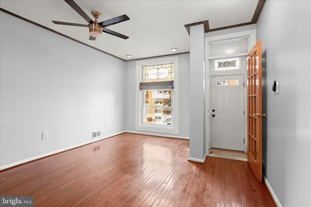 a view of an empty room with wooden floor and a window