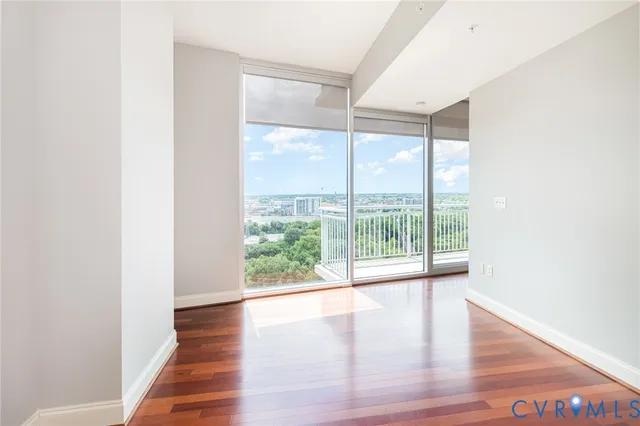 a view of an empty room with wooden floor and a window