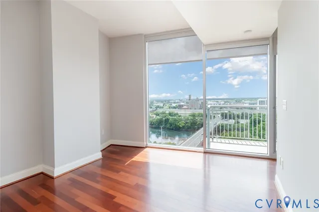 a view of an empty room with wooden floor and a window