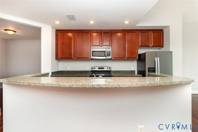 a kitchen with granite countertop a refrigerator and a stove top oven