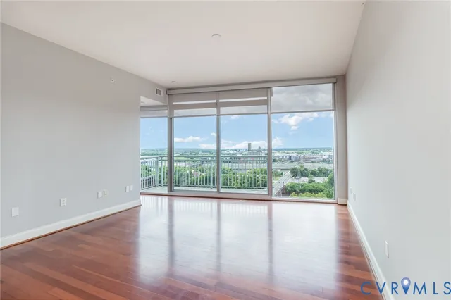 a view of empty room with wooden floor and fan