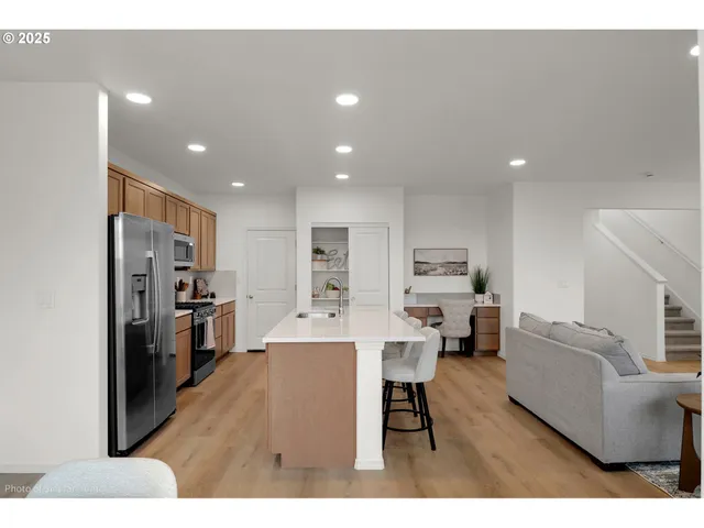 a living room with stainless steel appliances furniture and a kitchen view