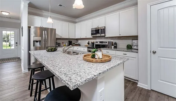 a kitchen with stainless steel appliances granite countertop a kitchen island hardwood floor sink stove and white cabinets