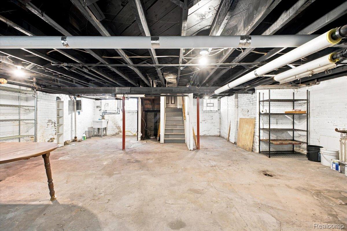 899 Edison Street Detroit, MI 48202 - Photo 30 of 37 Expansive unfinished basement featuring a concrete floor, exposed ceiling joists, white painted brick walls, and a utility sink