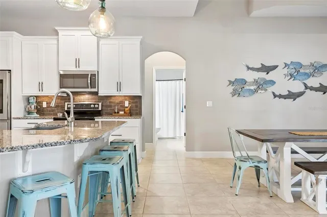 a kitchen with stainless steel appliances granite countertop a kitchen island a stove a table and chairs in it