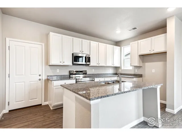 a kitchen with kitchen island granite countertop a sink cabinets and stainless steel appliances