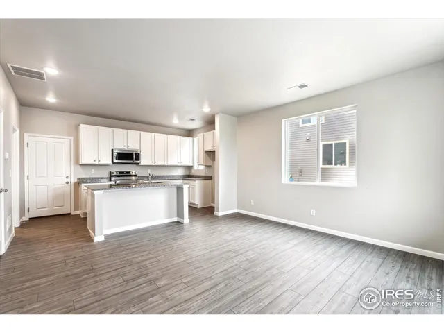 a kitchen with stainless steel appliances a refrigerator and white cabinets