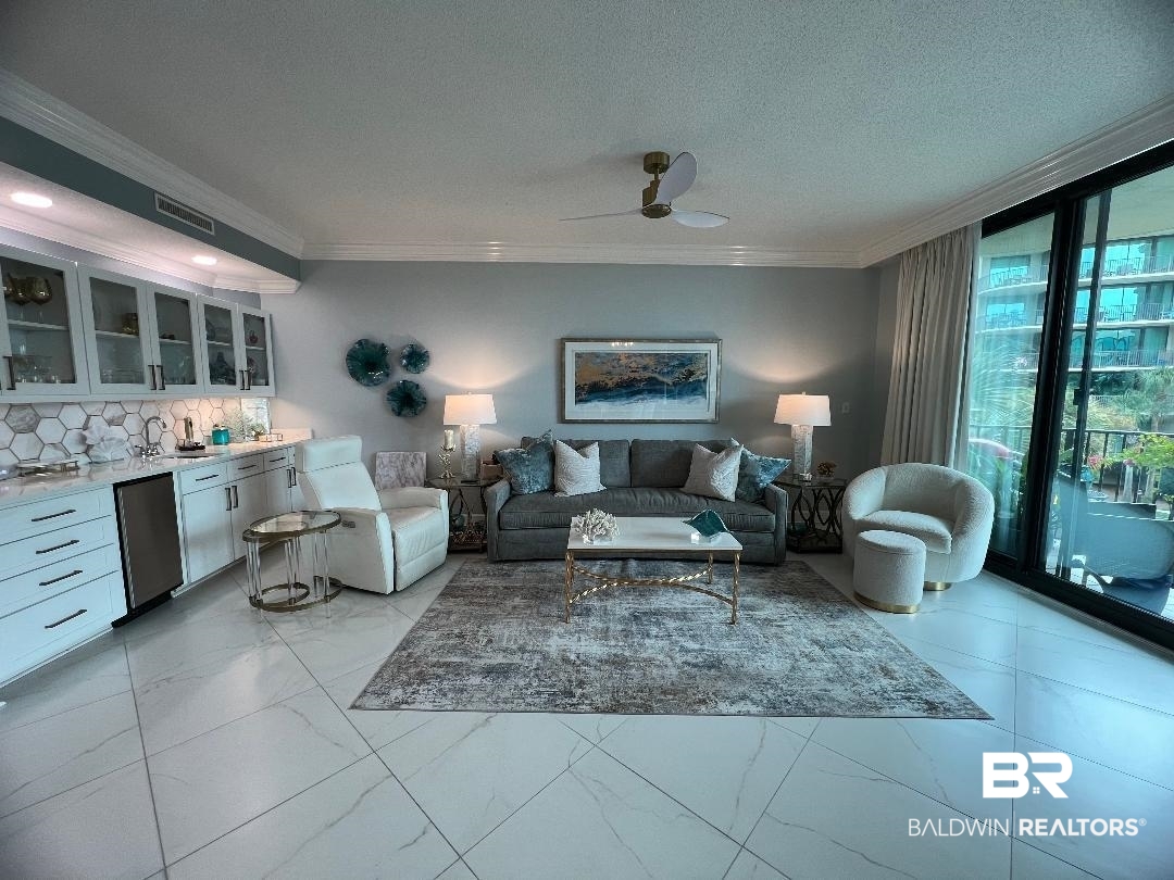 27580 Canal Road, Unit 1210 Orange Beach, AL 36561 - Photo 5 of 28 Living room with crown molding, expansive windows, bar with sink, ceiling fan, and a textured ceiling