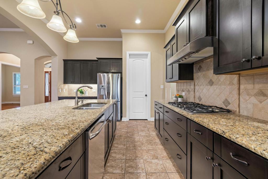 210 Mickelson Lane Georgetown, TX 78628 - Photo 15 of 39 a kitchen with stainless steel appliances granite countertop a sink a stove and a wooden cabinets