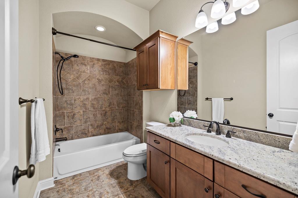 210 Mickelson Lane Georgetown, TX 78628 - Photo 24 of 39 a bathroom with a granite countertop sink a toilet and bathtub
