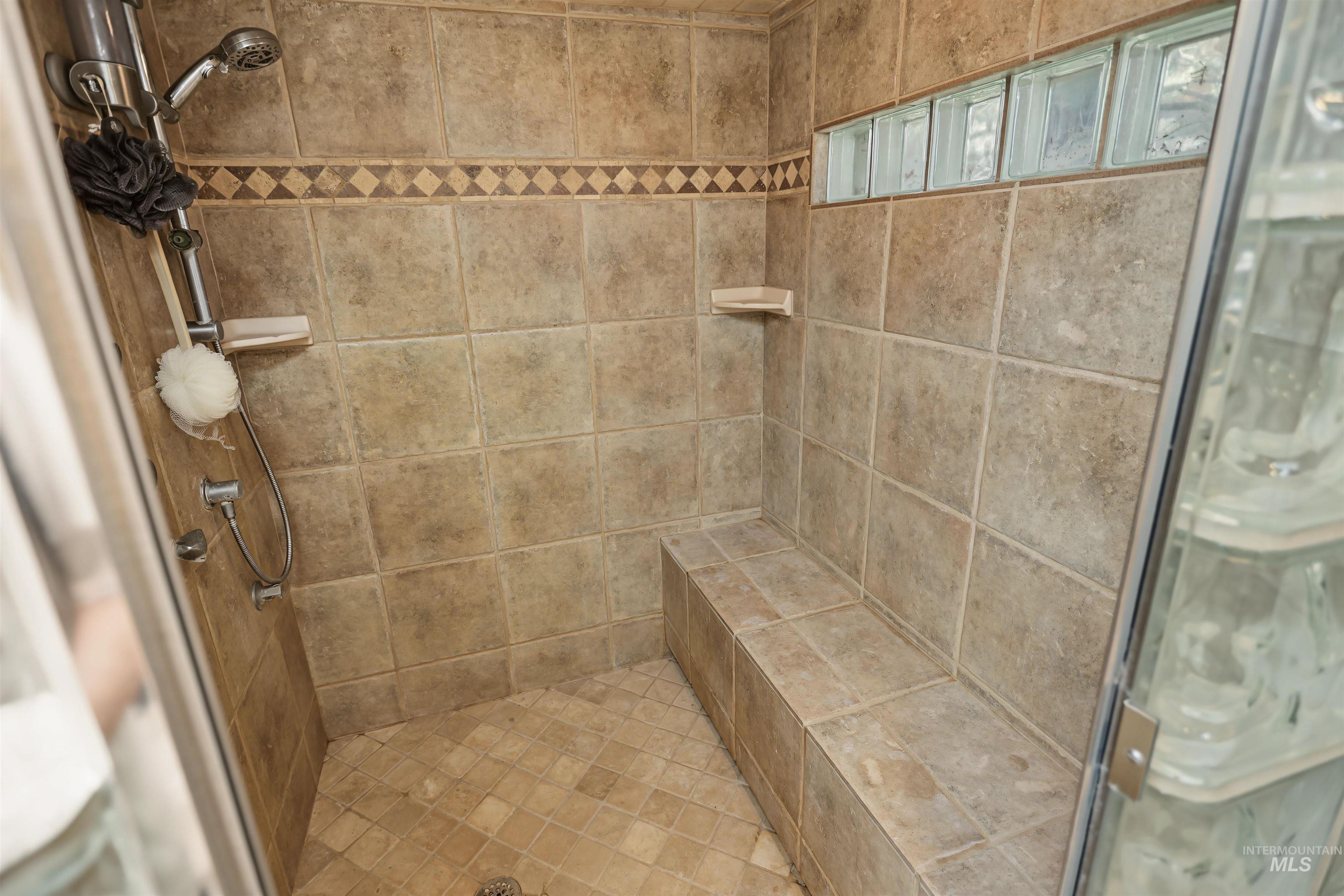 508 East Elm Avenue Parma, ID 83660 - Photo 25 of 50 Tiled shower enclosure featuring a built-in bench, glass block accent window, and dual shower heads