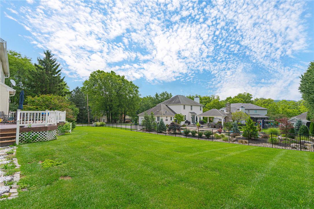 102 Sutton Road Easton, PA 18045 - Photo 71 of 83 A spacious green lawn stretches alongside a secure metal fence under expansive skies.