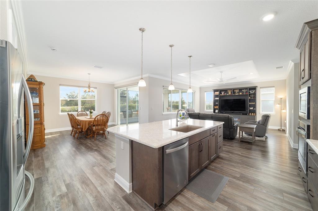 8457 Southwest 97th Circle Ocala, FL 34481 - Photo 26 of 62 a open kitchen with stainless steel appliances granite countertop a stove top oven a sink dishwasher a dining table and chairs with wooden floor