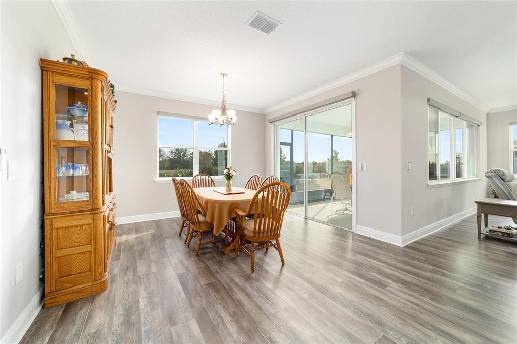 8457 Southwest 97th Circle Ocala, FL 34481 - Photo 29 of 62 a dining room with furniture wooden floor a potted plant and a chandelier