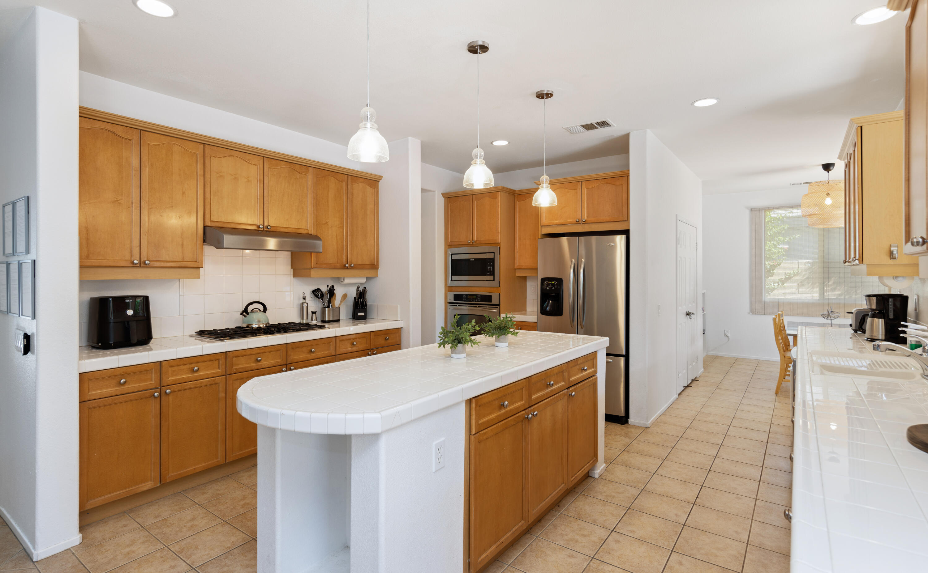 83299 Stagecoach Road Indio, CA 92203 - Photo 12 of 44 a large kitchen with stainless steel appliances a stove a sink a refrigerator and white cabinets with wooden floor