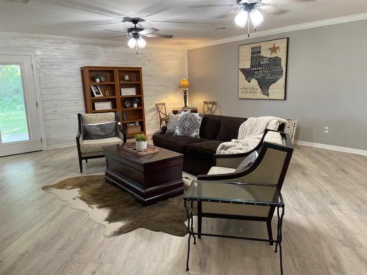 1402 Posey Brewer Road Sunset, TX 76270 - Photo 4 of 19 Living area featuring ornamental molding, wood walls, light wood-type flooring, and a ceiling fan