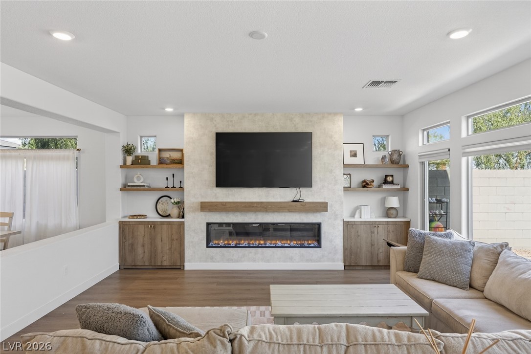 10446 Emerald Rye Street Las Vegas, NV 89183 - Photo 10 of 37 A well-lit living space features a linear fireplace and hardwood-style flooring, perfect for gatherings.