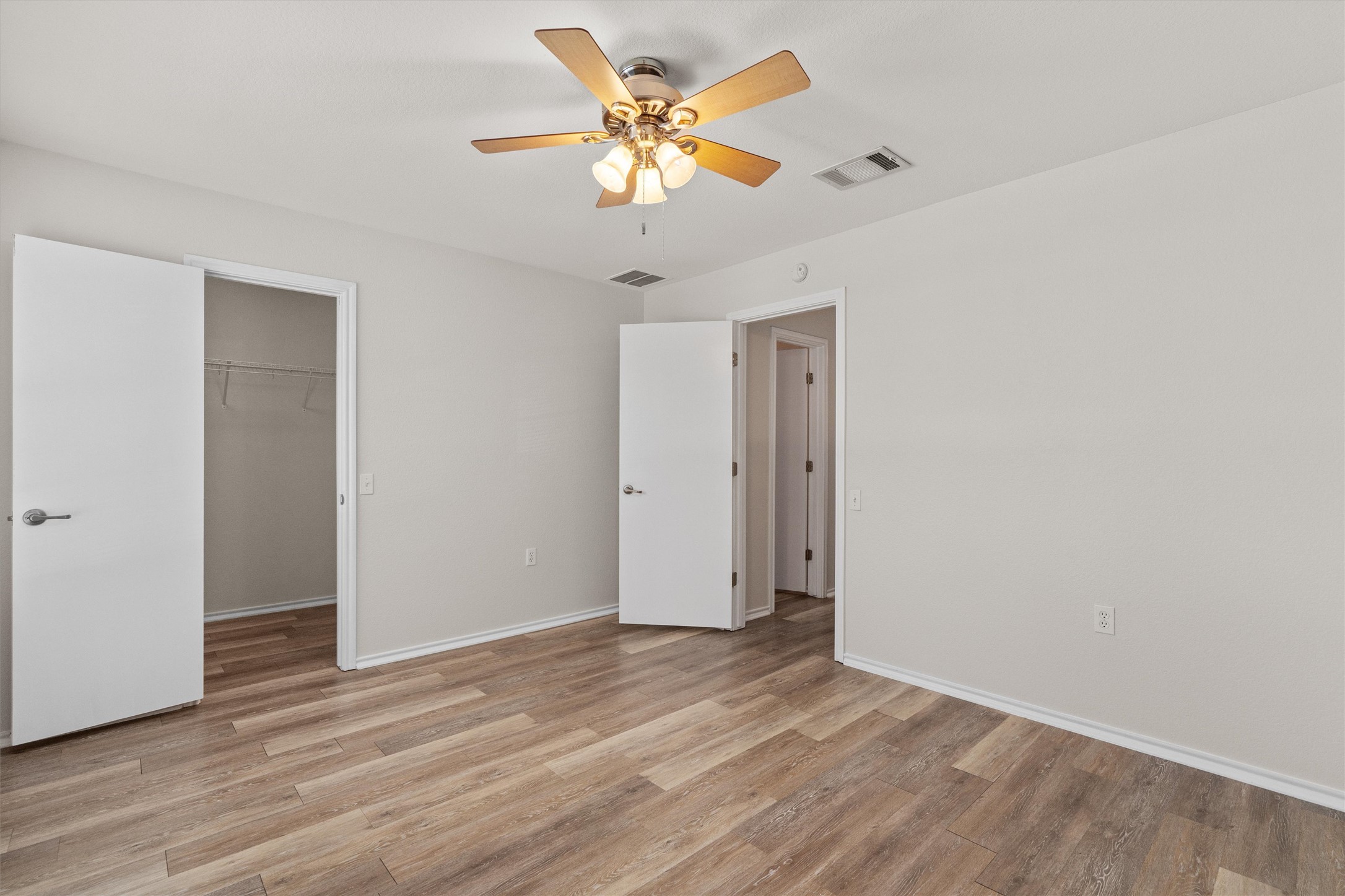 5825 Silver Screen Drive Austin, TX 78747 - Photo 22 of 40 A quiet bedroom features elegant wood flooring, crisp white walls, and a warm-toned ceiling fan.