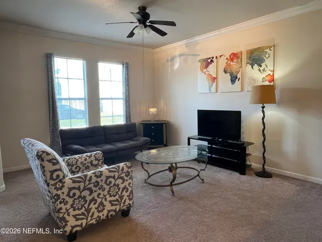 a living room with furniture a flat screen tv and a window