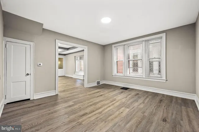 a view of an empty room with wooden floor and windows