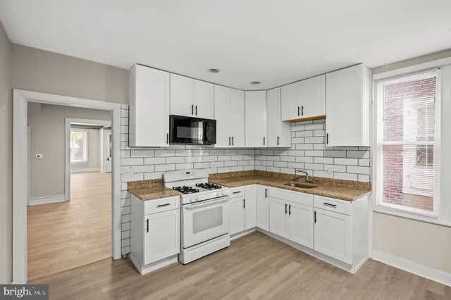 a kitchen with granite countertop white cabinets and white appliances