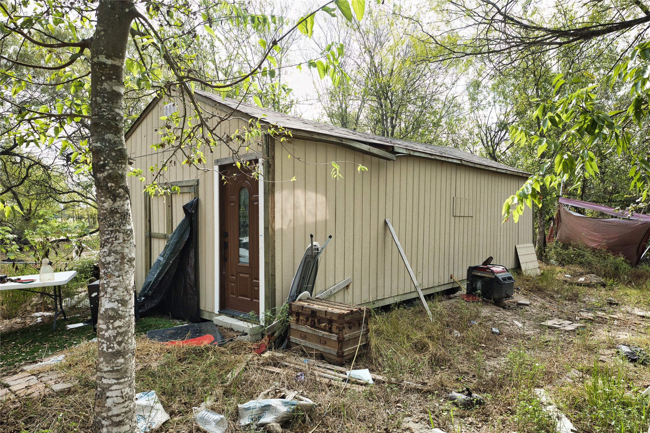 2900 Salt Flat Road Luling, TX 78648 - Photo 13 of 17 A detached wood outbuilding offers versatile storage space tucked among mature trees.