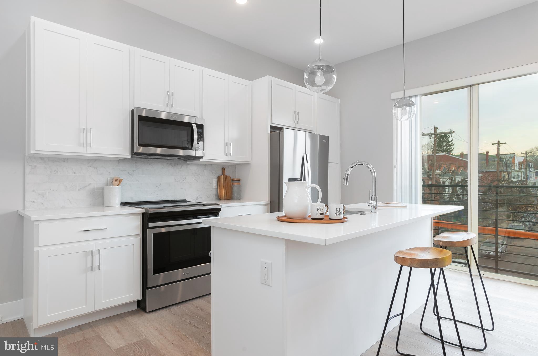 52 West Washington Lane, Unit 200 Philadelphia, PA 19144 - Photo 7 of 30 a kitchen with kitchen island white cabinets and stainless steel appliances
