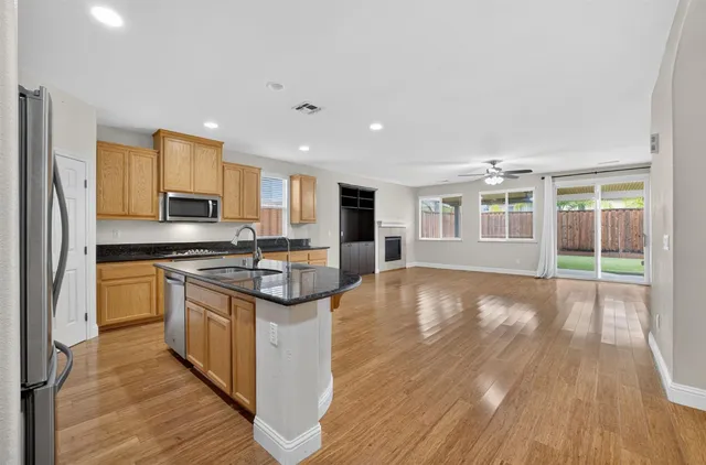 a large kitchen with stainless steel appliances granite countertop a stove and a wooden floors