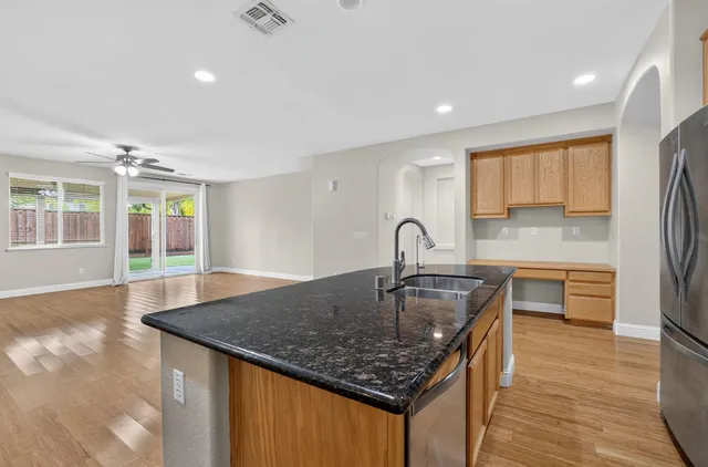 a kitchen with stainless steel appliances granite countertop a sink a stove and a wooden floors