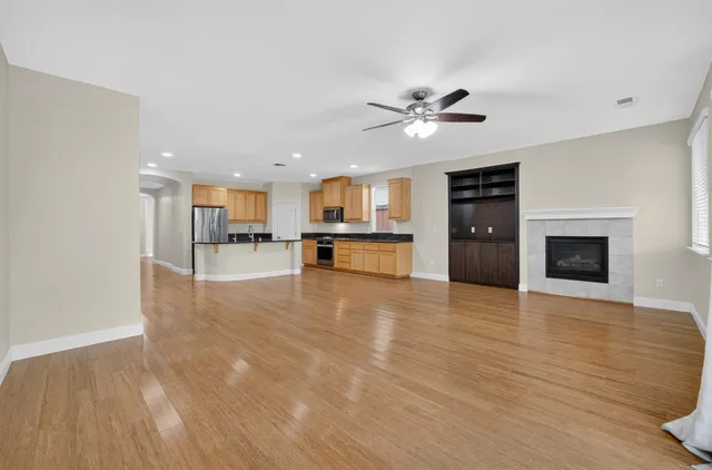 a view of a kitchen with a stove cabinets a ceiling fan and wooden floor