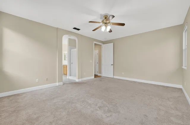 a view of an empty room with chandelier fan