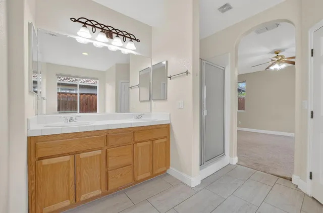a spacious bathroom with a granite countertop sink a mirror and a shower