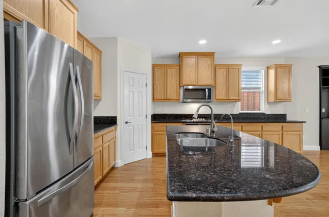 a kitchen with stainless steel appliances granite countertop a refrigerator a stove and a sink