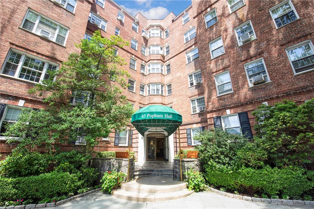 a front view of a building with garden and plants