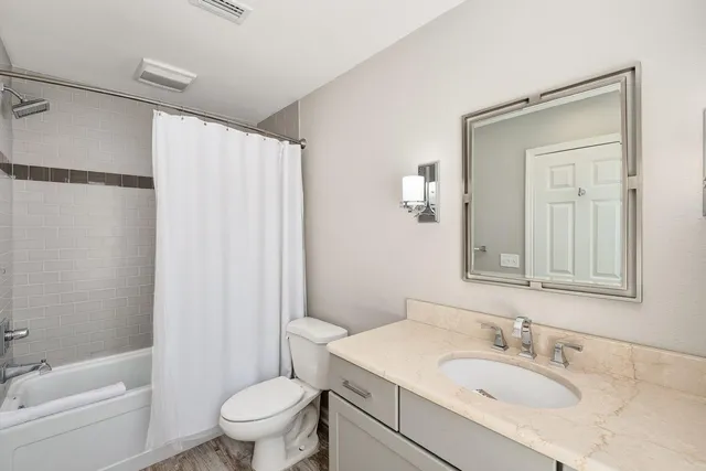 a view of a white house next to a yard with potted plants