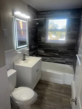 a bathroom with a sink a toilet a mirror a vanity and window