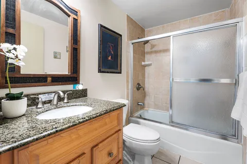 a bathroom with a granite countertop sink toilet and shower glass cabinet