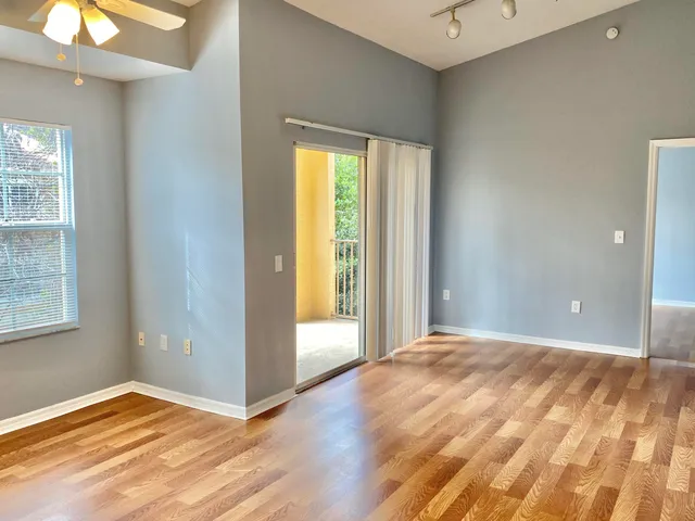 a view of an empty room with wooden floor and a window