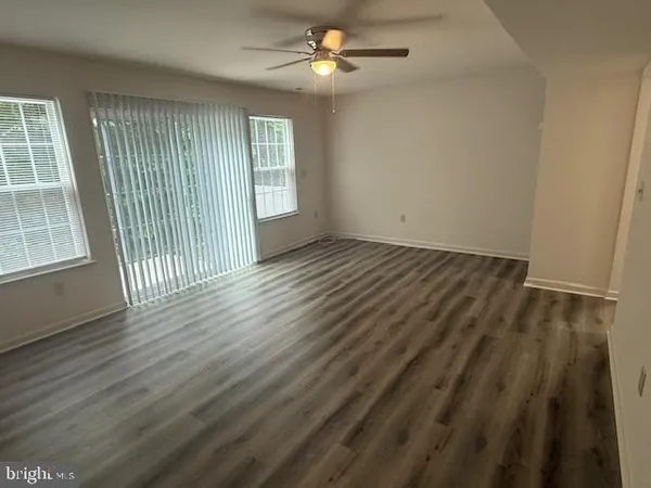 an empty room with wooden floor fan and windows